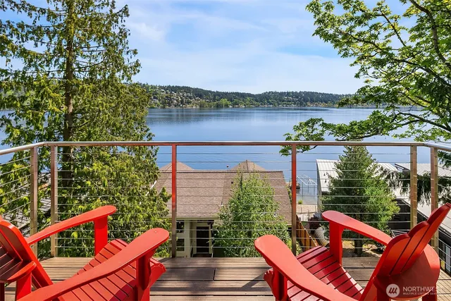 a view of a balcony with wooden chairs and floor to ceiling window and wooden fence