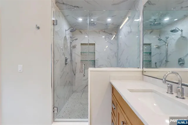 a bathroom with a sink shower and a mirror