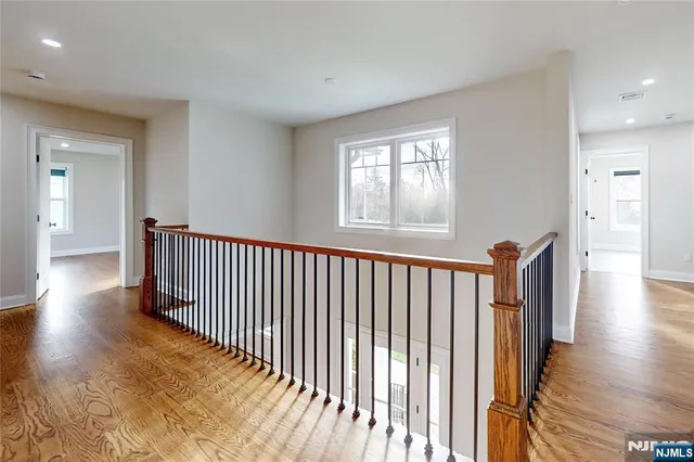 a view of a hallway with wooden floor and a bathroom
