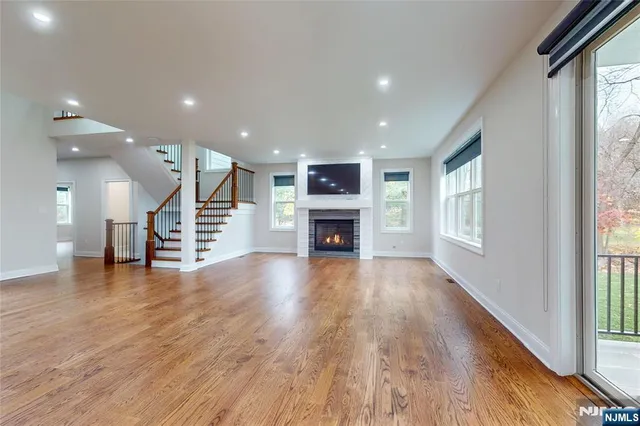 an empty room with wooden floor fireplace and windows