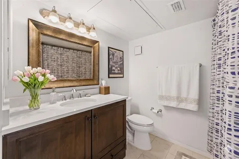 a bathroom with a granite countertop sink a toilet and mirror