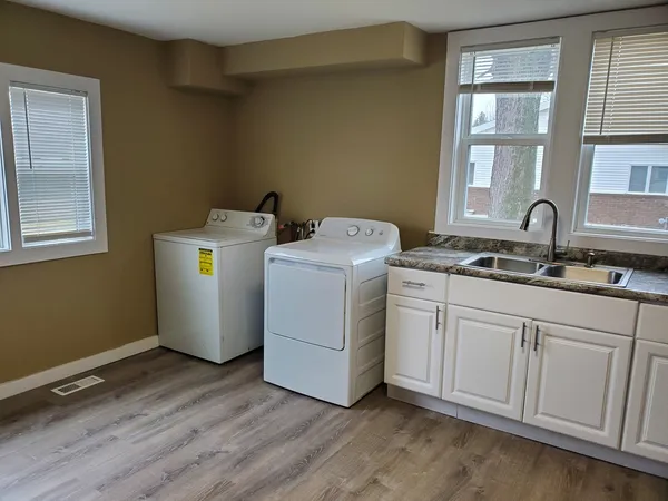 a utility room with wooden floor washer and dryer