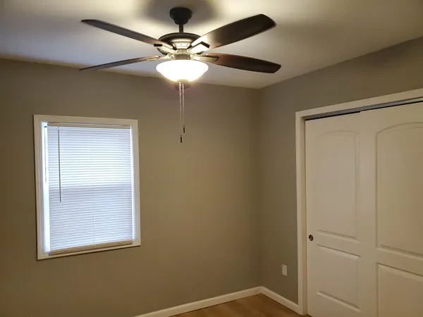 an empty room with a window and a fan