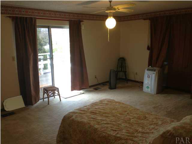 7495 Gunter Road Pensacola, FL 32526 - Photo 13 of 25 Master Bedroom on second level. Portable air conditioner will convey with the property. Sliding glass doors onto open balcony area.