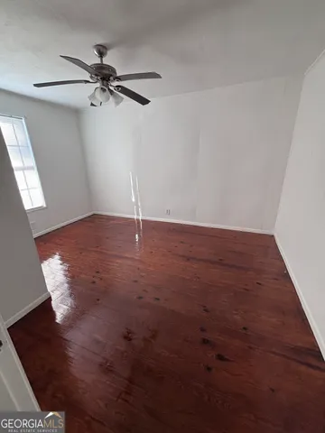 an empty room with wooden floor fan and windows