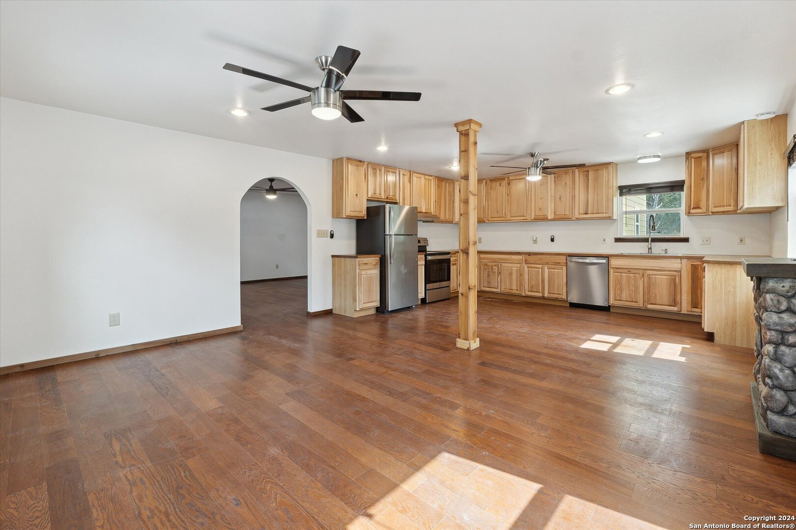 497 Black Bass Road Lakehills, TX 78063 - Photo 15 of 54 a view of a kitchen with cabinets stainless steel appliances wooden floor and a window