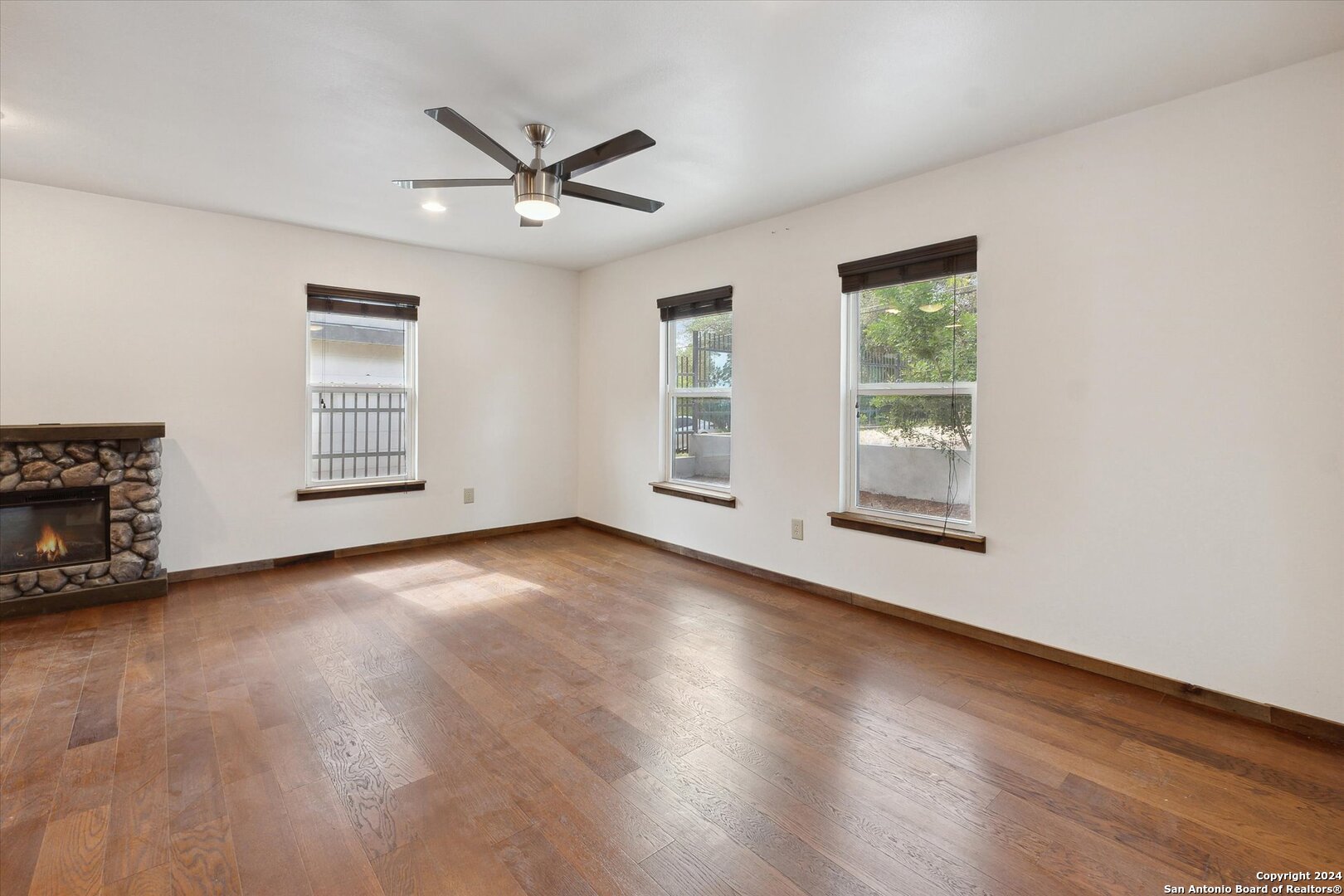 497 Black Bass Road Lakehills, TX 78063 - Photo 16 of 54 an empty room with wooden floor fan and windows