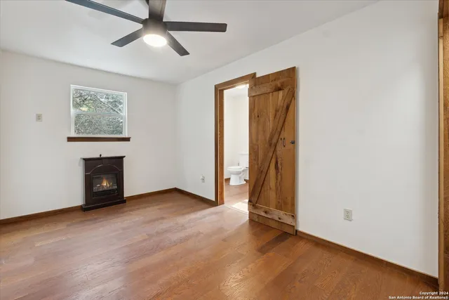 a view of an empty room with wooden floor and a ceiling fan