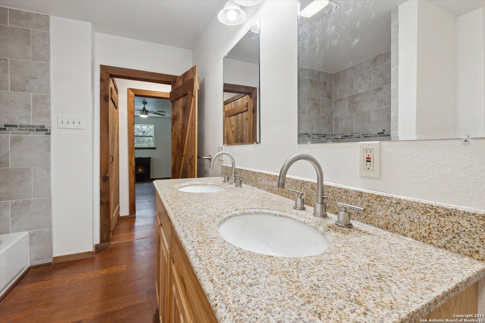 497 Black Bass Road Lakehills, TX 78063 - Photo 29 of 54 a bathroom with a granite countertop sink a mirror and vanity