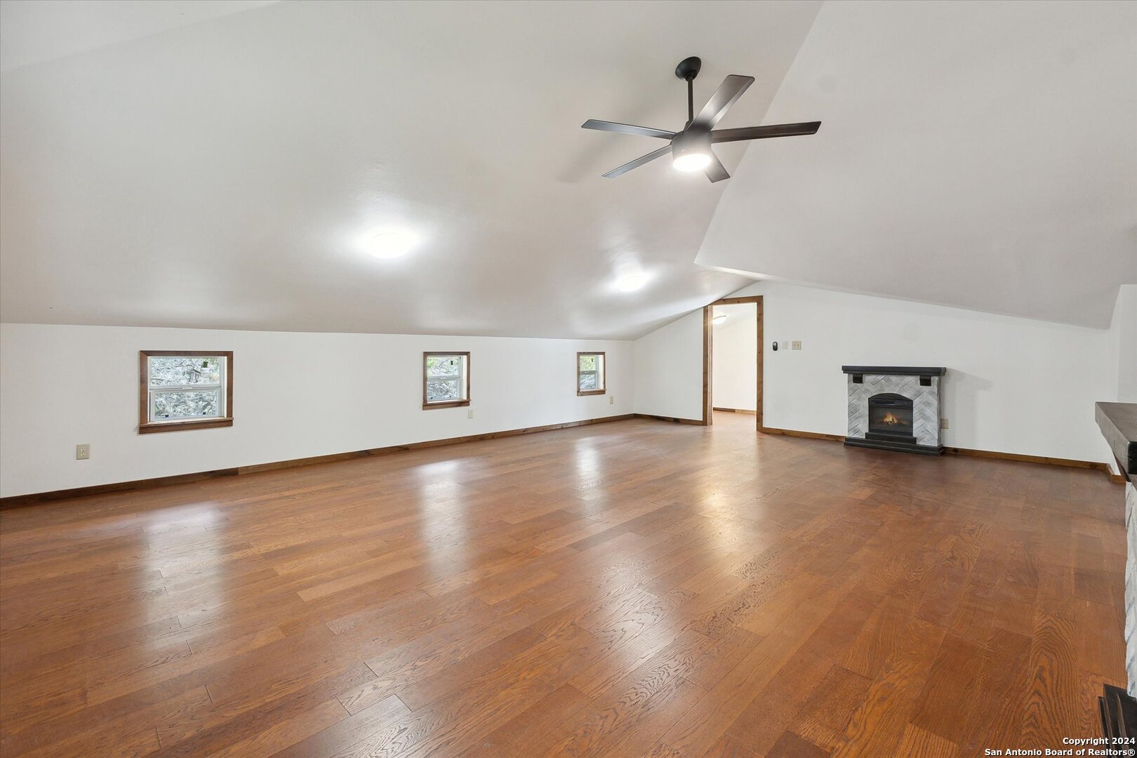 497 Black Bass Road Lakehills, TX 78063 - Photo 33 of 54 a view of a livingroom with fireplace a ceiling fan and wooden floor