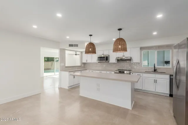 a large kitchen with kitchen island a sink a stove and a refrigerator