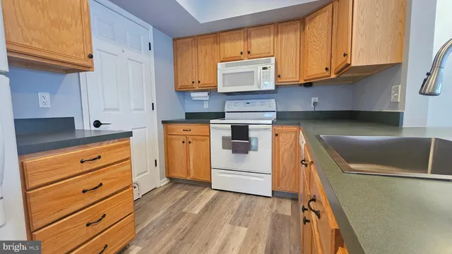 a kitchen with granite countertop wooden cabinets and white appliances