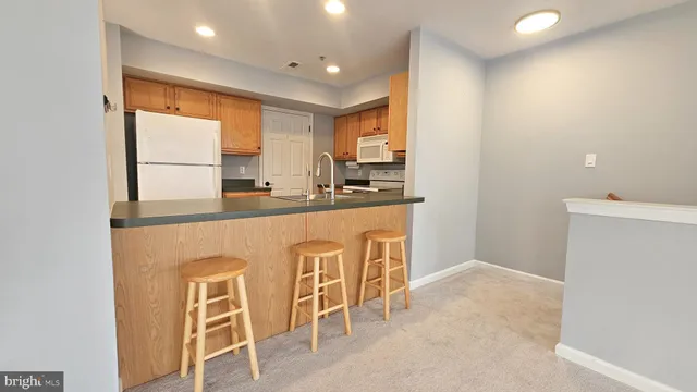 a kitchen with stainless steel appliances granite countertop a sink a stove a refrigerator with white cabinets and wooden floor