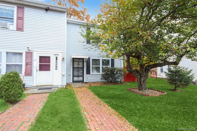 a front view of a house with a garden and trees