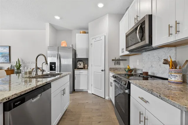 a kitchen with stainless steel appliances granite countertop a sink a stove and a microwave