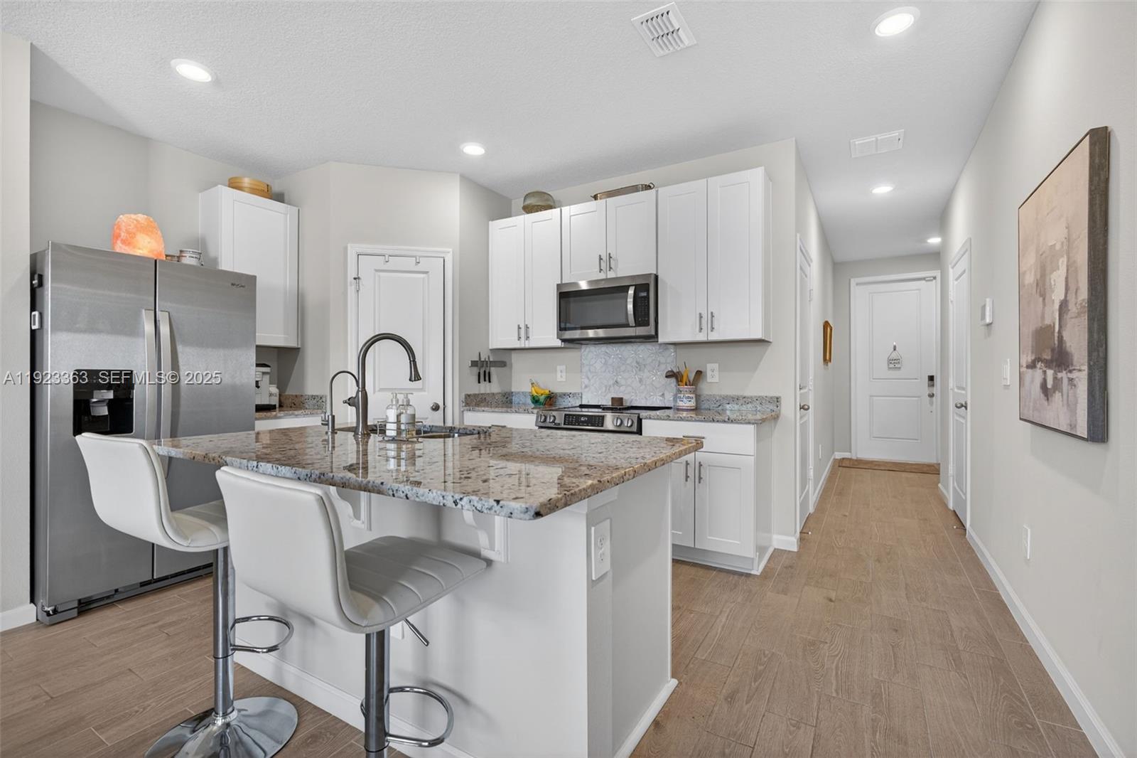 5746 Southeast Edgewater Circle Stuart, FL 34997 - Photo 10 of 38 a kitchen with stainless steel appliances granite countertop a sink a stove a refrigerator cabinets and a dining table with wooden floor