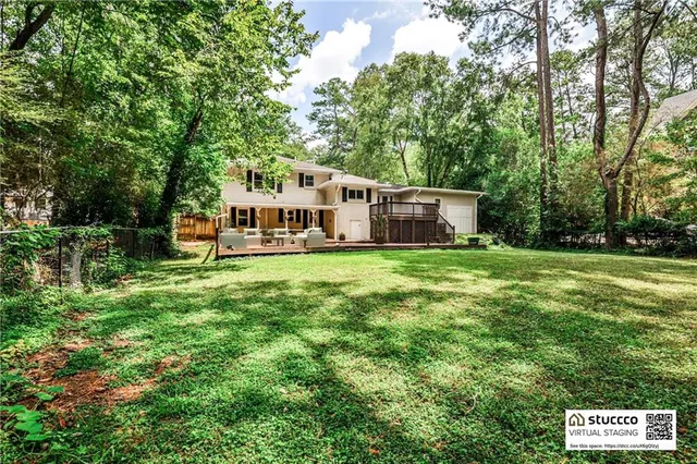 a view of a house with a big yard potted plants and large tree