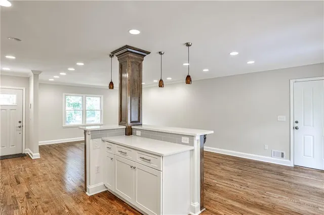 a view of a kitchen counter top space with stainless steel appliances wooden floor and living room view