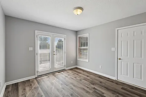 an empty room with wooden floor and windows