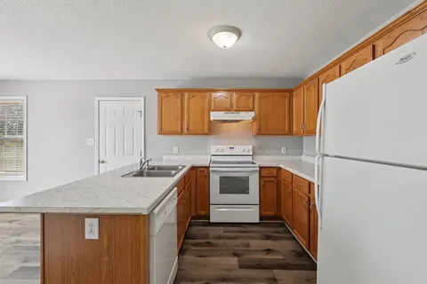 a kitchen with granite countertop a sink stove and refrigerator