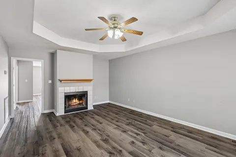 a view of an empty room with wooden floor and a fireplace