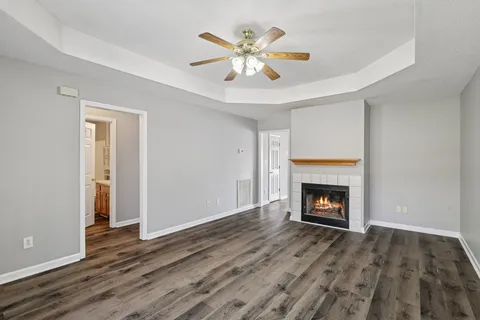 a view of an empty room with wooden floor fireplace and a window