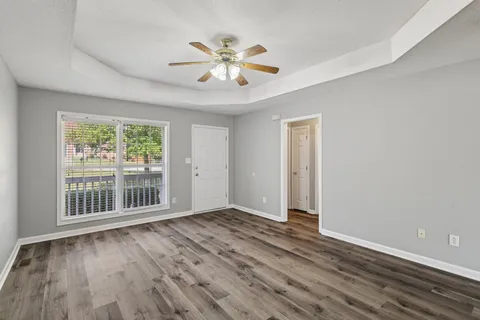 a view of an empty room with wooden floor and a window