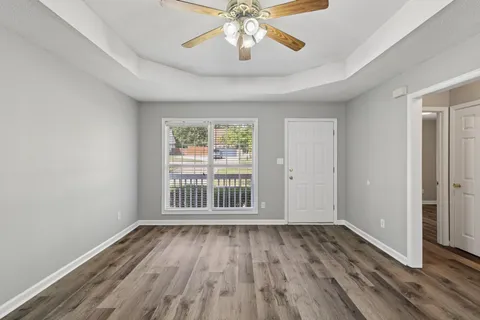 an empty room with wooden floor chandelier and windows