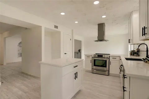 a kitchen with white cabinets appliances and a window