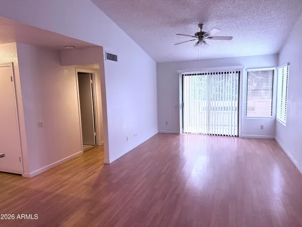 a view of an empty room with wooden floor and a window