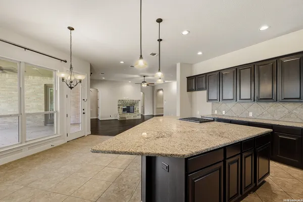 a kitchen with kitchen island granite countertop wooden cabinets and a chandelier