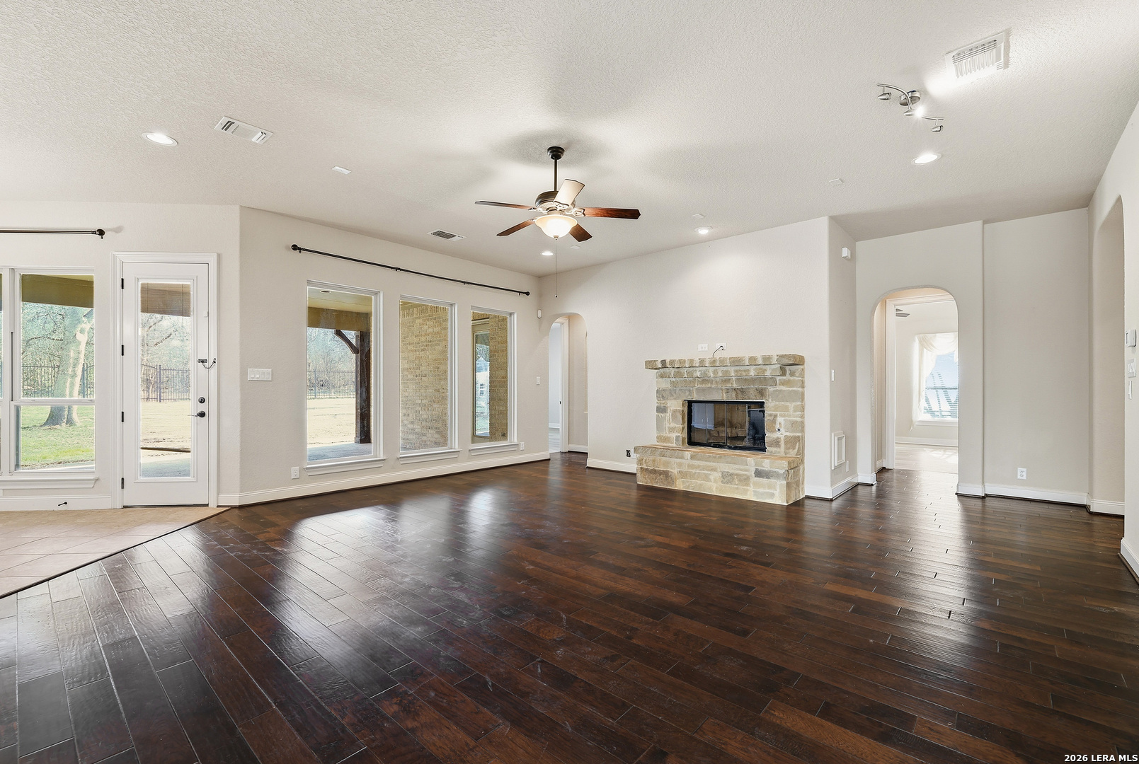 19414 Arrowood Place Garden Ridge, TX 78266 - Photo 6 of 25 an empty room with wooden floor fireplace and windows