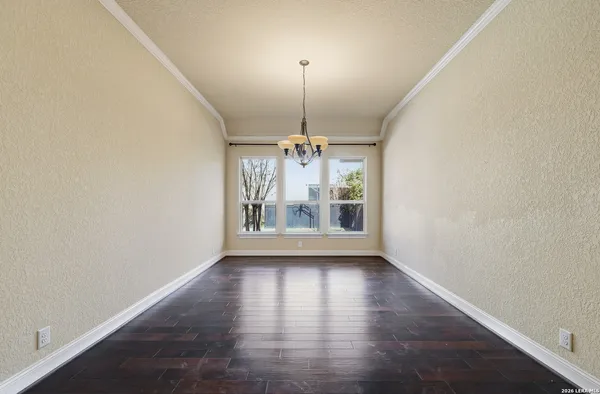 an empty room with wooden floor chandelier and window