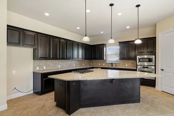 a large kitchen with kitchen island a large counter top stainless steel appliances and cabinets