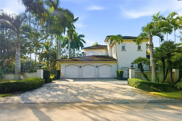 a view of an house with a big yard and palm trees
