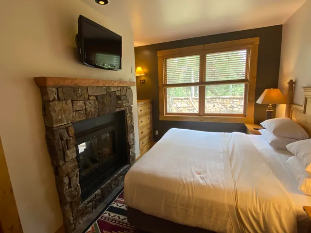 a bedroom with a bed a flat screen tv and a window