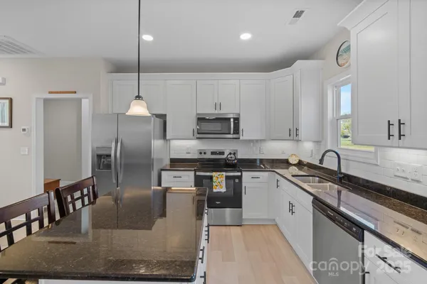 a kitchen with granite countertop a sink a stove and cabinets