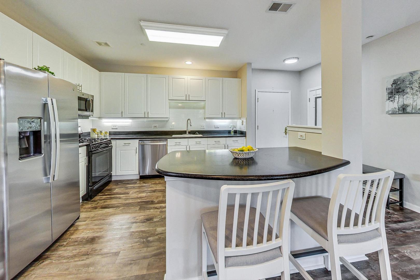 640 McHenry Road, Unit 203 Wheeling, IL 60090 - Photo 19 of 41 a kitchen with stainless steel appliances granite countertop a sink a stove a refrigerator a table and chairs