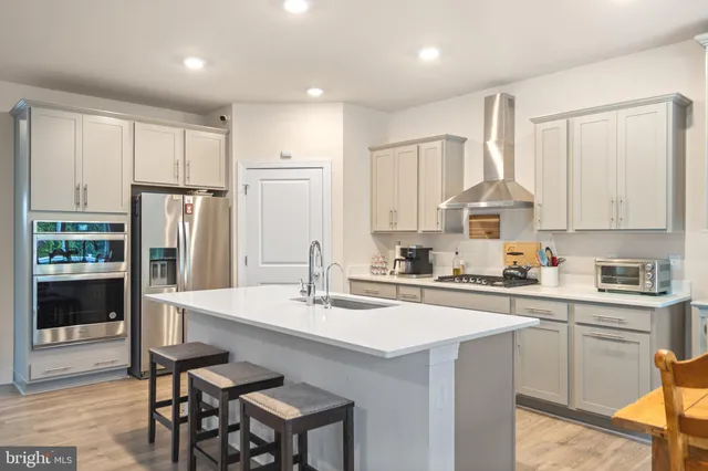 a kitchen with stainless steel appliances granite countertop a sink a stove a refrigerator cabinets and chairs