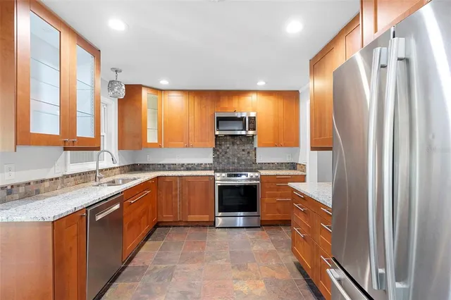 a large kitchen with stainless steel appliances granite countertop a refrigerator and a sink