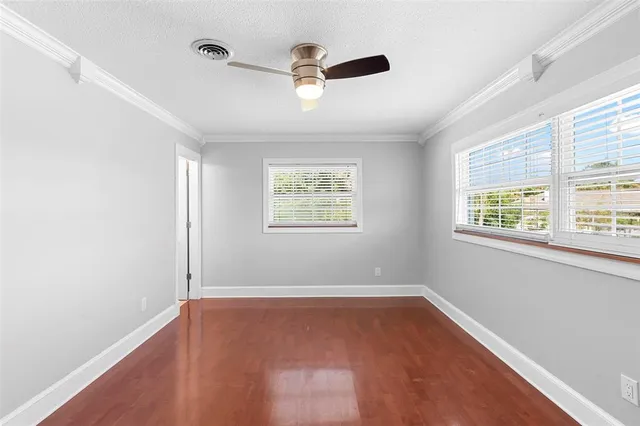 an empty room with ceiling fan and windows