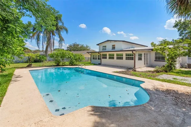 a view of a swimming pool with a yard and palm trees