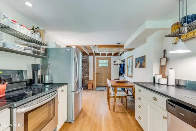 a kitchen with granite countertop lots of white cabinets stainless steel appliances a large window and a counter space