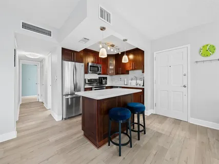 a kitchen with stainless steel appliances granite countertop a refrigerator a sink dishwasher a stove and a dining table with wooden floor