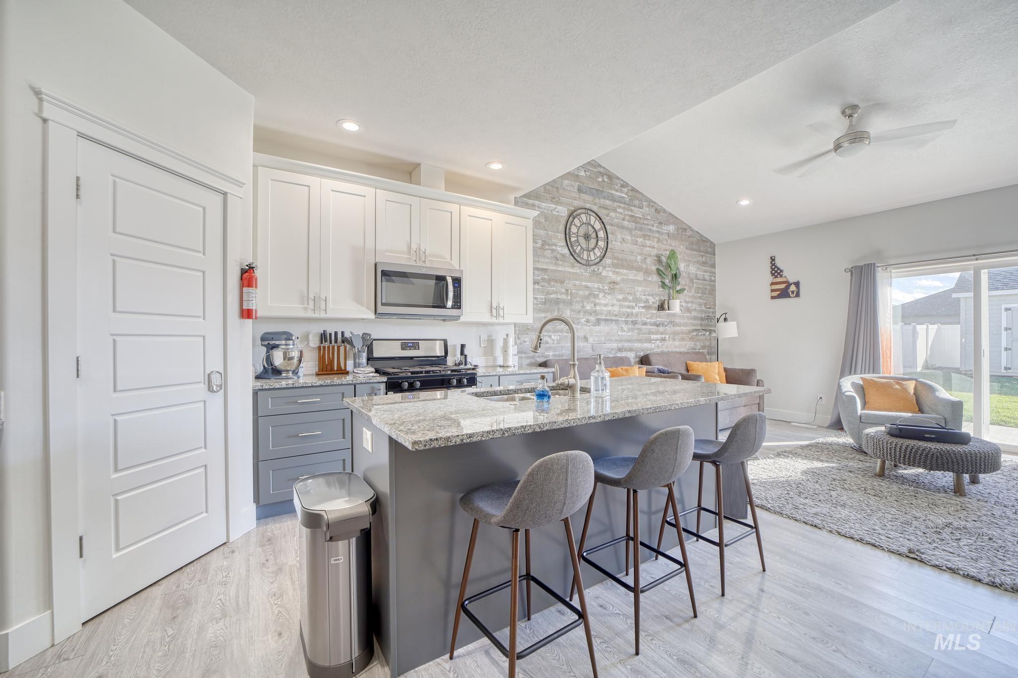 1087 Easy Avenue Twin Falls, ID 83301 - Photo 24 of 25 Kitchen with lofted ceiling, light stone countertops, a breakfast bar area, white cabinets, and open floor plan