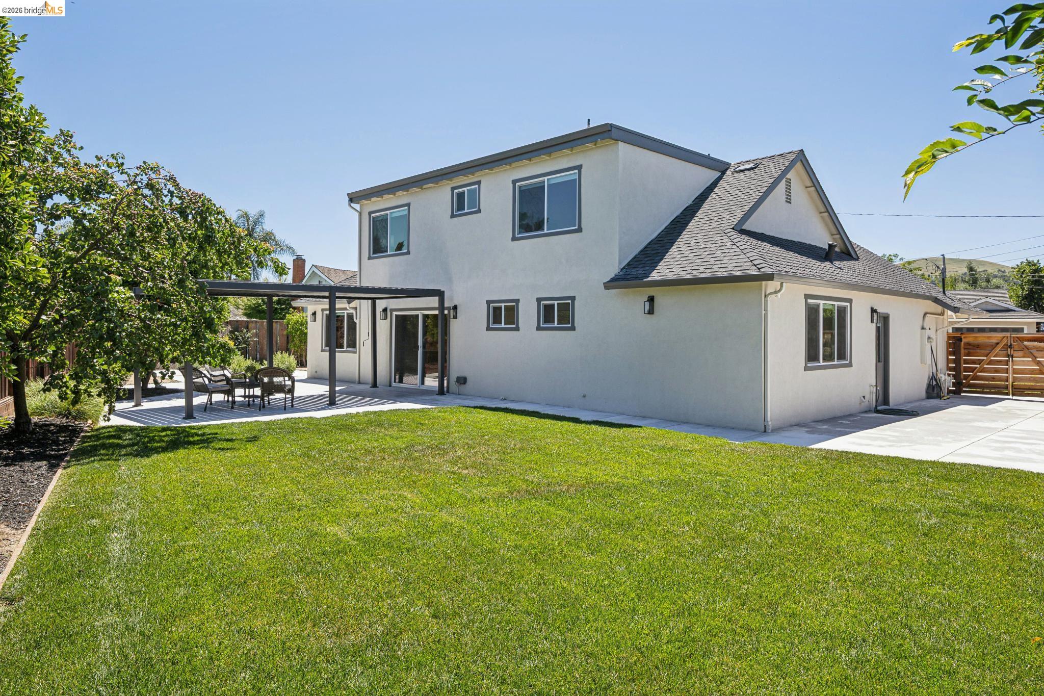 11 Belinda Court San Ramon, CA 94583 - Photo 31 of 33 Expansive rear yard featuring a manicured lawn, concrete patio with a modern pergola, and sliding glass door access to the interior