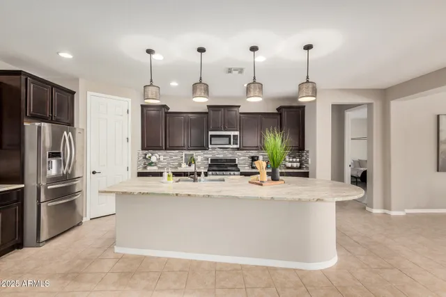 a view of a kitchen with kitchen island a counter top space a sink stainless steel appliances and cabinets