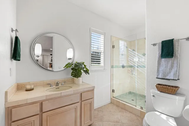 a bathroom with a granite countertop sink a toilet and a mirror
