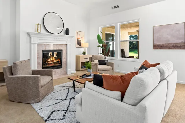 a living room with furniture a fireplace and a large window