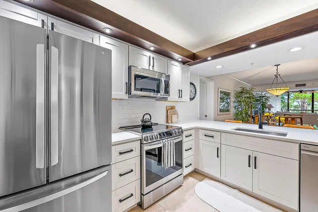 a kitchen with white cabinets stainless steel appliances and a window